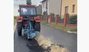 Traktors ar arklu brauc pa tikko ieklātu asfaltu Glivicē Polijā