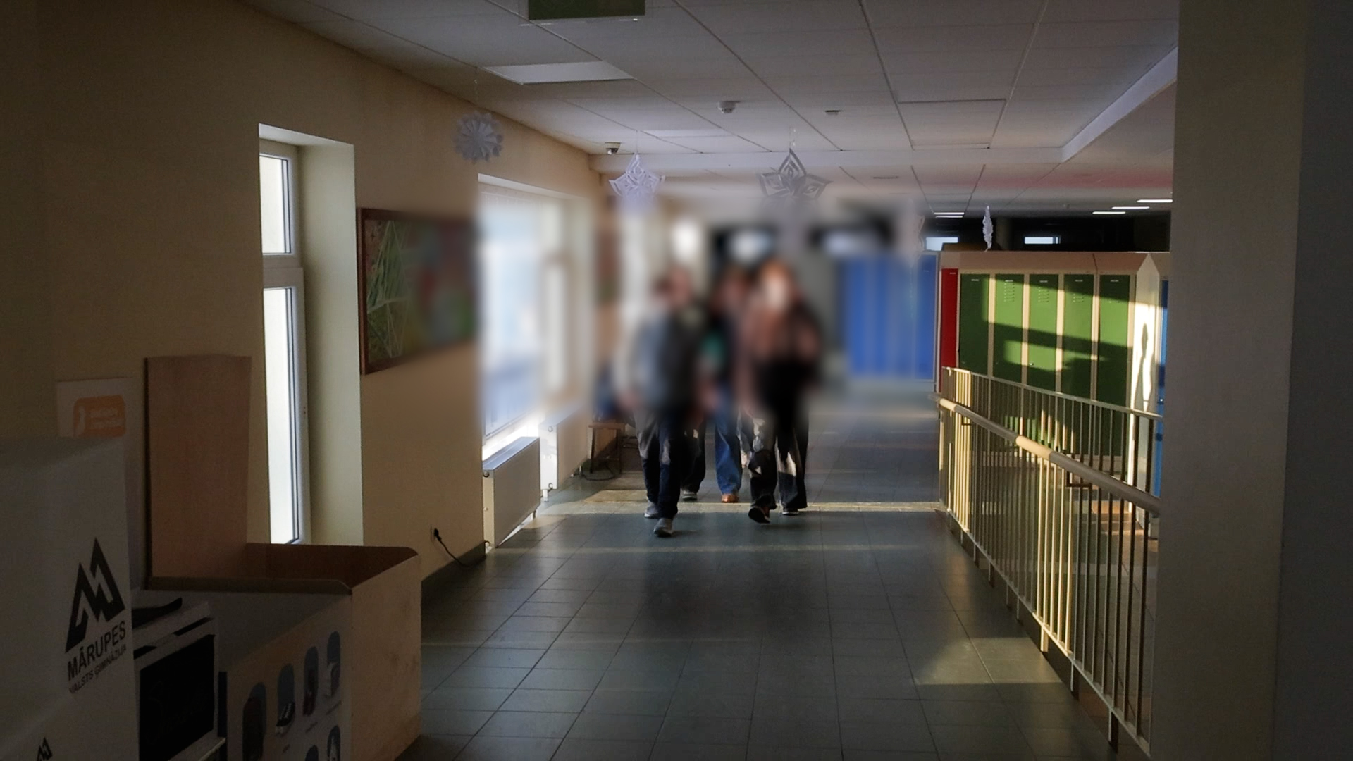 Cilvēki skolas gaitenī pie skolēnu skapīšiem