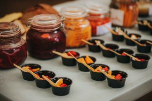 Burciņas ar dažādu krāsu konservētiem produktiem un degustācijas trauciņi ar dārzeņiem