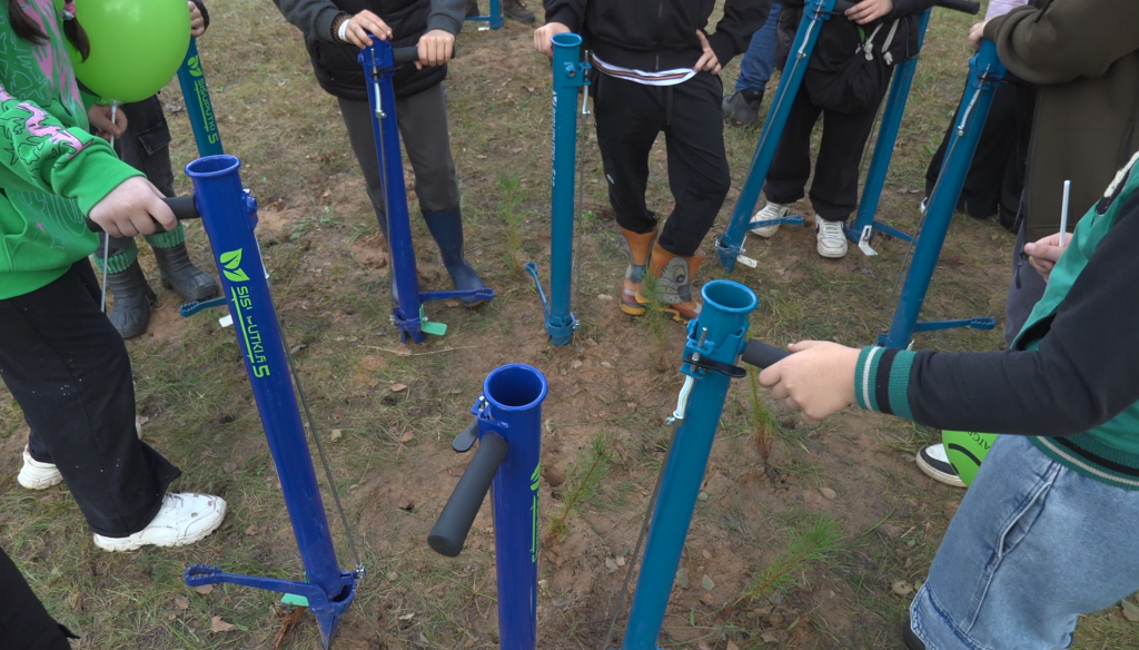 Skolēni izmēģina meža stādīšanas instrumentus