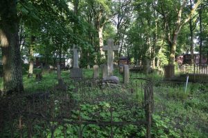 Veca kapsēta ar kapu pieminekļiem, krustiem un metāla nožogojumiem