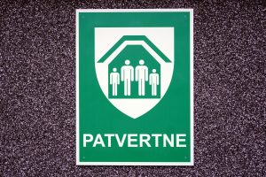 Zaļa patvertnes norādes zīme pie ēkas