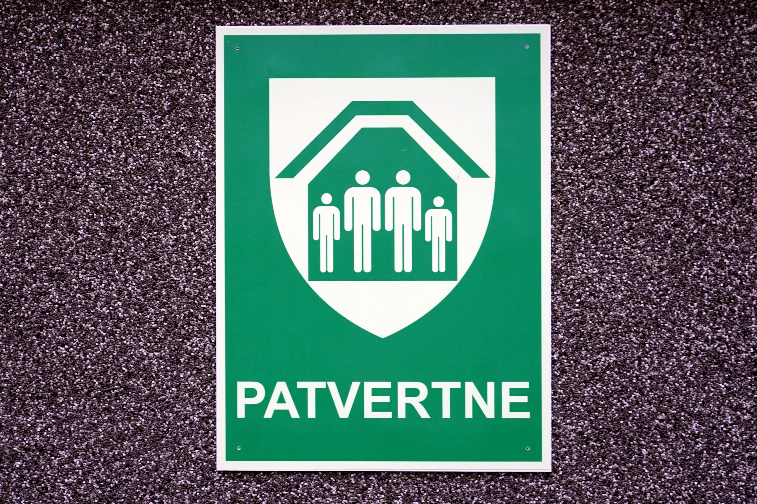 Zaļa patvertnes norādes zīme pie ēkas