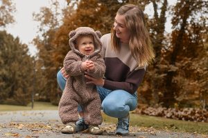 Mamma ar bērnu, kuram mugurā lācīša tipa rāpulītis