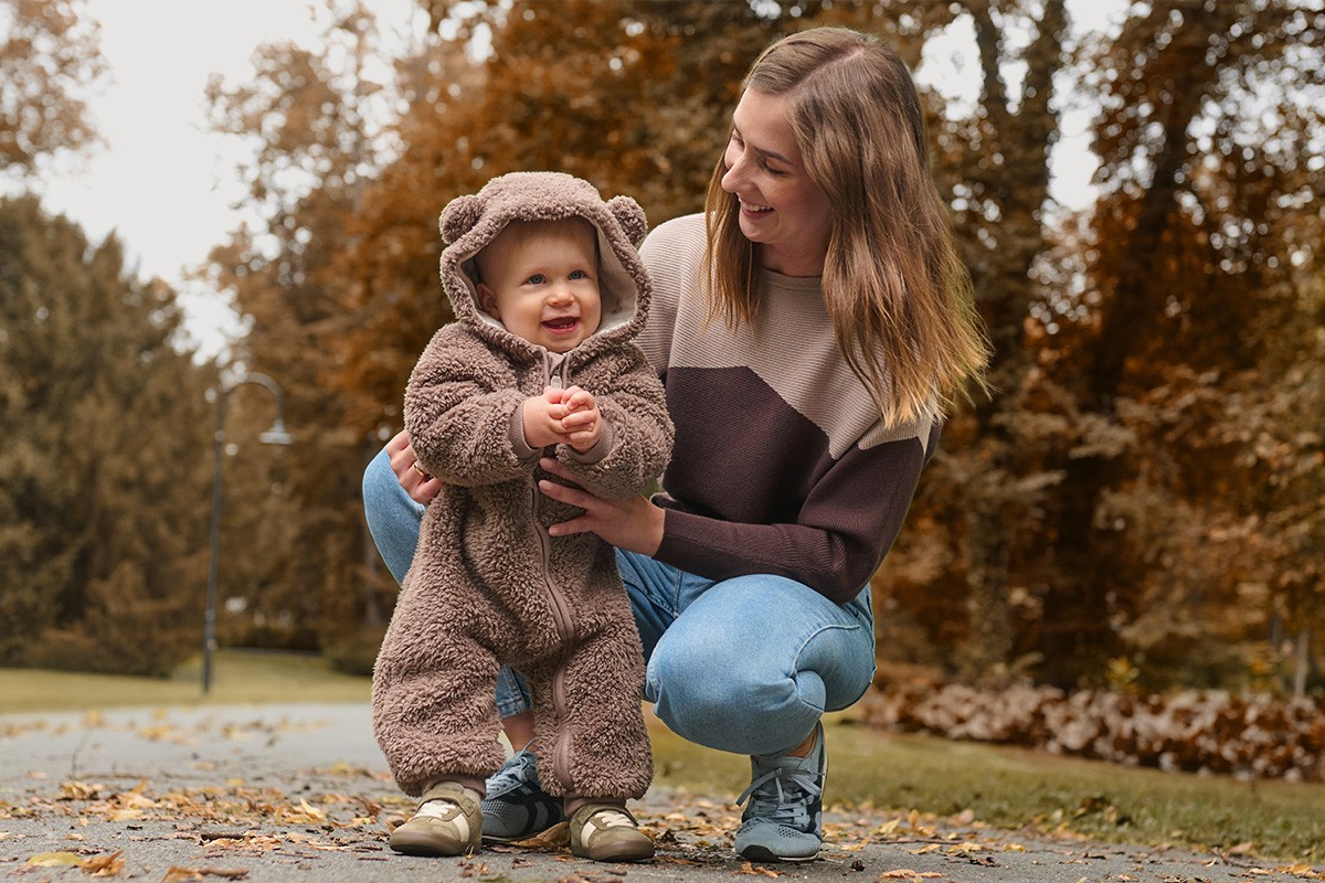 Mamma ar bērnu, kuram mugurā lācīša tipa rāpulītis