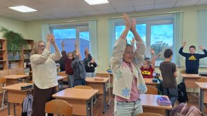 Skolēni kopā ar skolotāju piedalās aktivitātē klasē