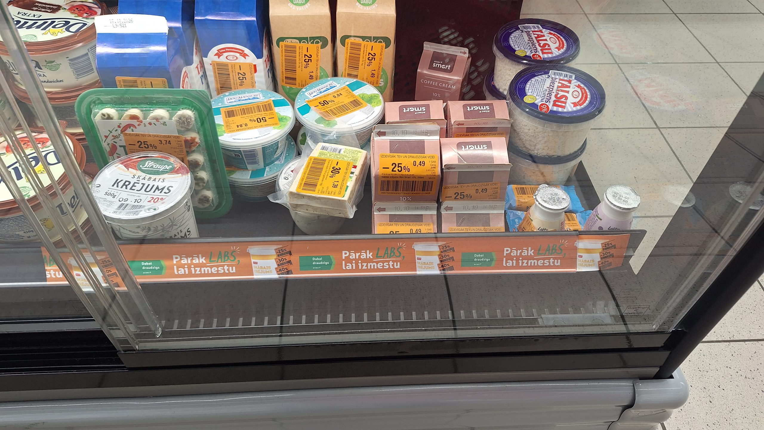 Pārtikas produkti ar samazinātām cenām veikala ledusskapī, kur izvietota iniciatīvas “Pārāk labs, lai izmestu” norāde.