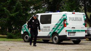 Pašvaldības policijas darbinieks pie policijas auto
