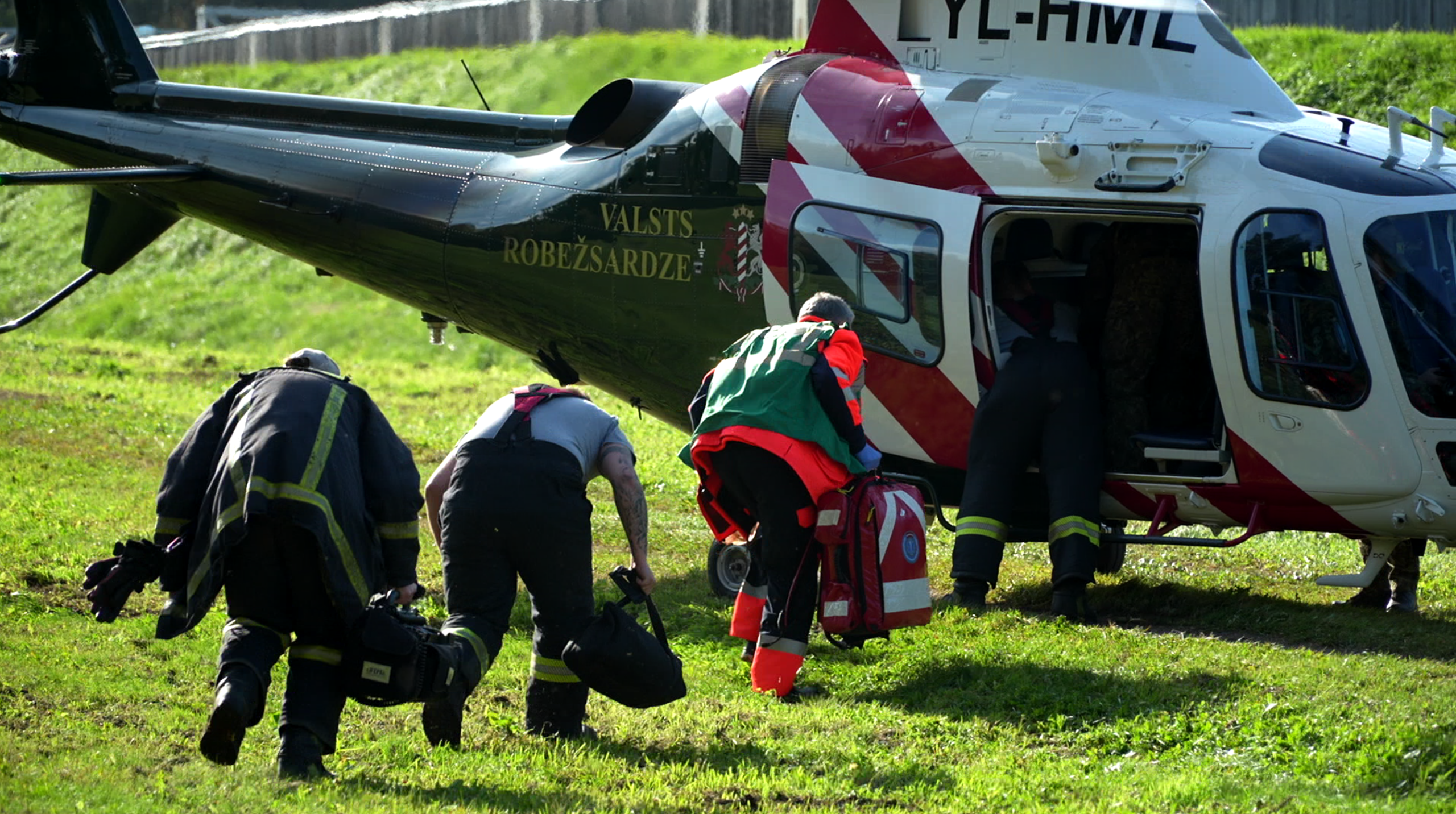 Valsts robežsardzes helikopters un glābšanas dienestu pārstāvji ar aprīkojumu starpiestāžu taktisko mācību laikā.