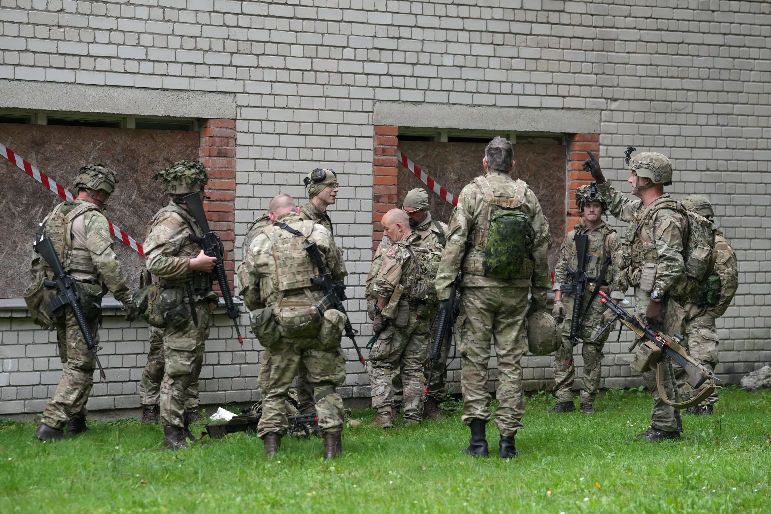 Karavīri militārajā ekipējumā pie ēkas militāro mācību laikā
