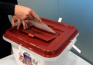 Vēlētājs ievieto vēlēšanu aploksni balsošanas urnā