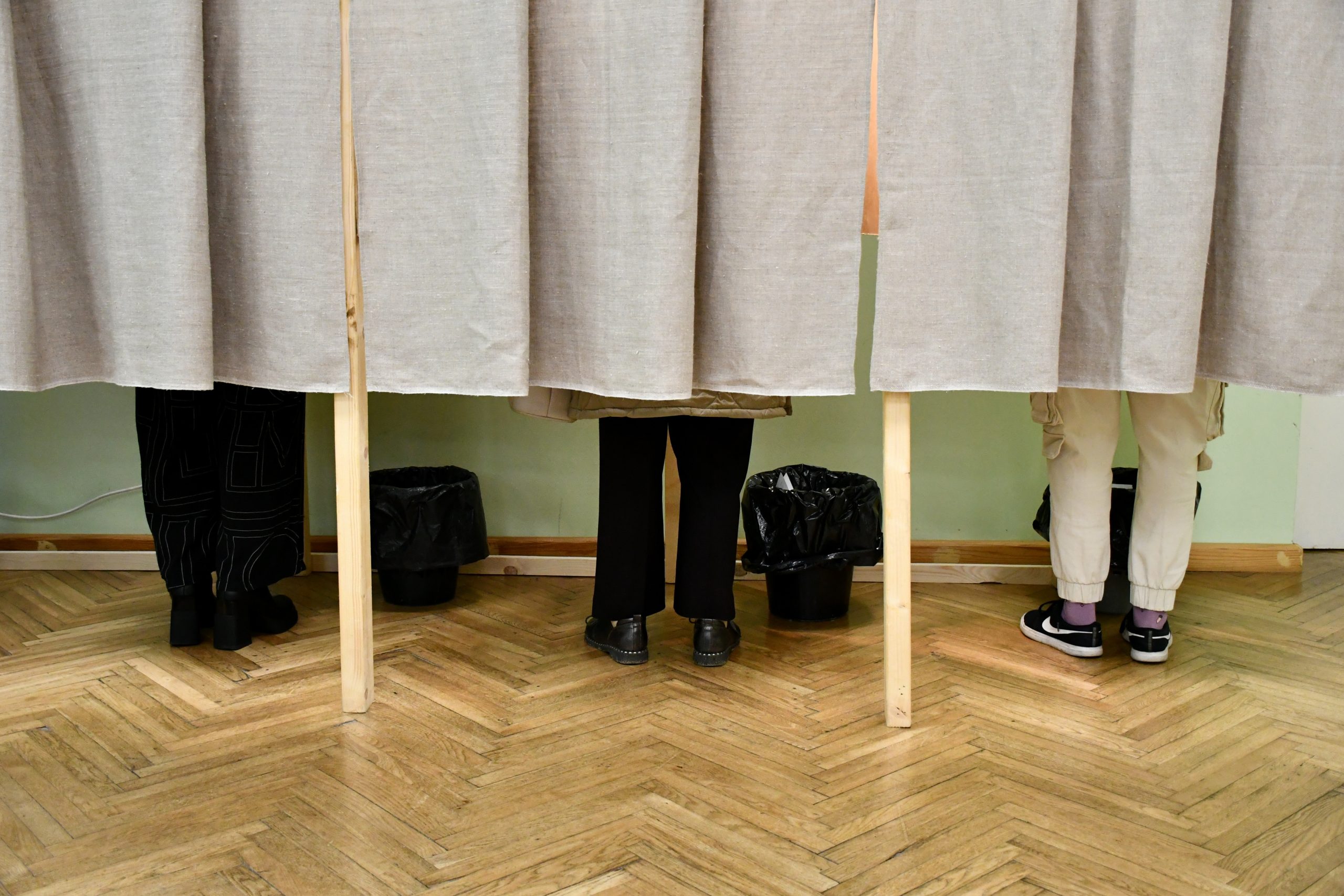 Vēlētāji aiz aizkariem aizpilda vēlēšanu zīmes vēlēšanu iecirknī