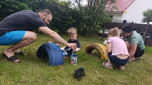 Ģimene kopā ar bērniem krāso riepas rotaļu laukumam