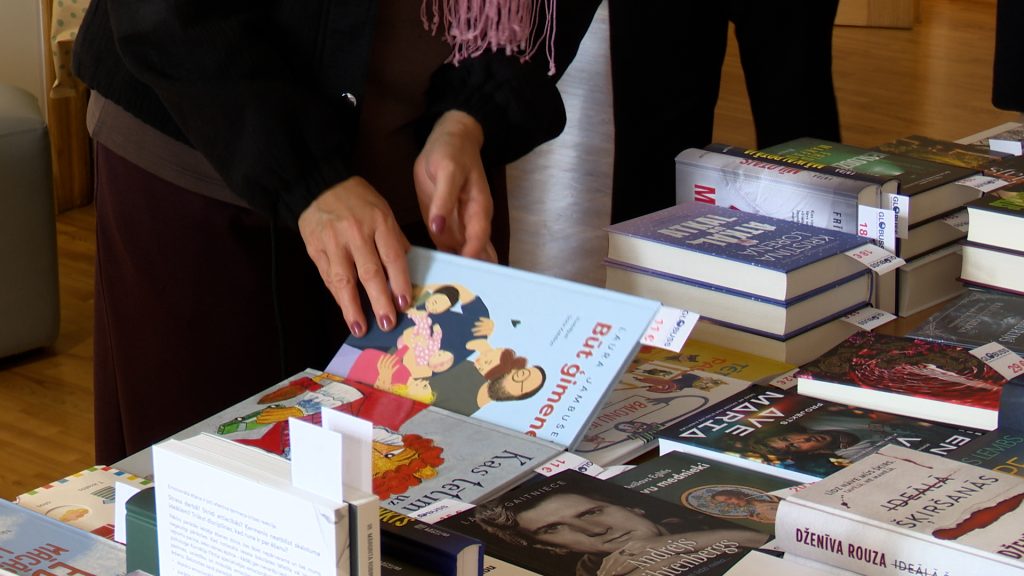 Apmeklētāja šķirsta grāmatu uz galda izkārtotā grāmatu piedāvājumā