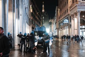 Itālijas policisti aiztur cilvēku pie policijas transportlīdzekļa Milānas centrā.