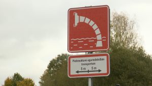 Sarkana ugunsdzēsības ūdens ņemšanas vietas zīme ar norādi par piebrauktuvi ugunsdzēsības transportam.
